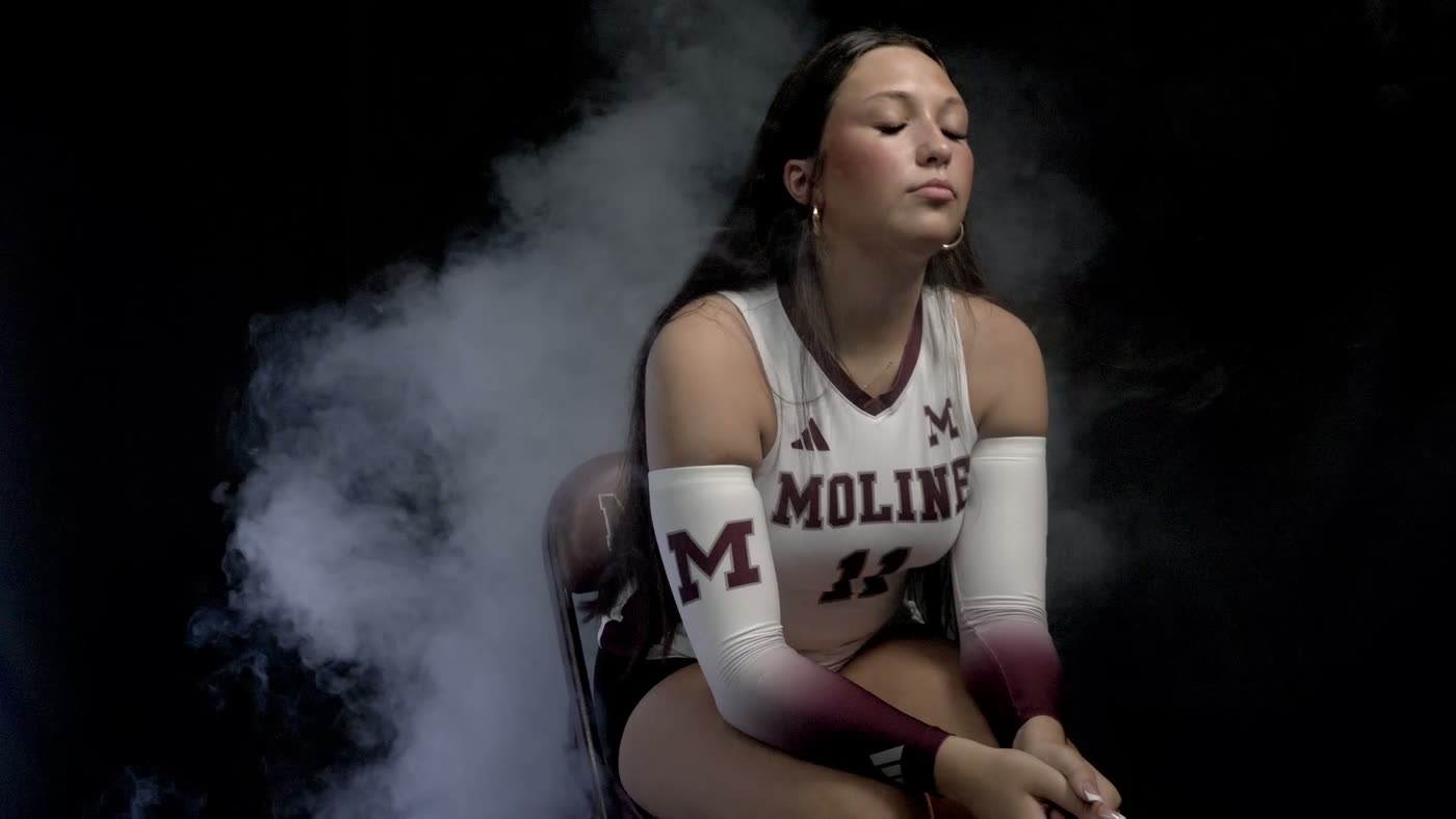 Seated volleyball player lit against black with haze drifting behind her